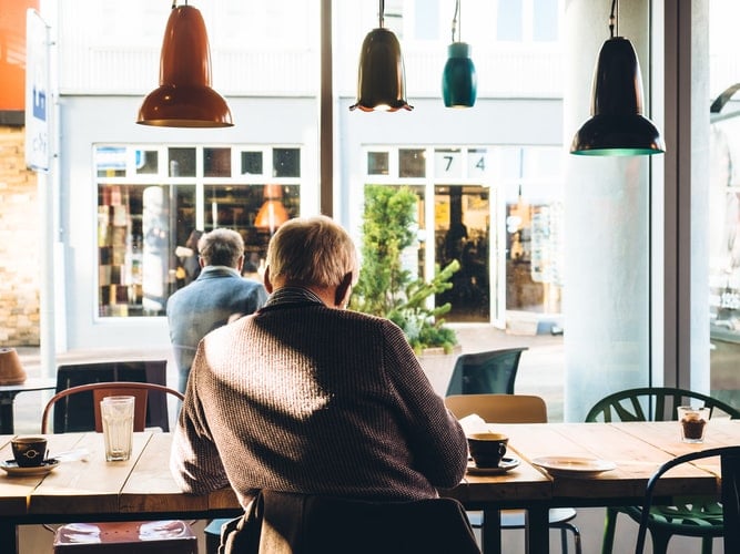 Older man sitting inside coffee shop.