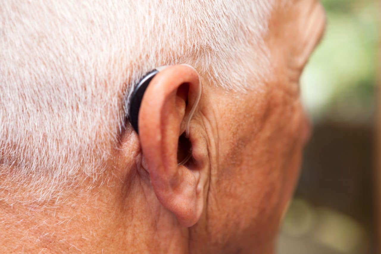 Older man wearing a behind-the-ear hearing aid.