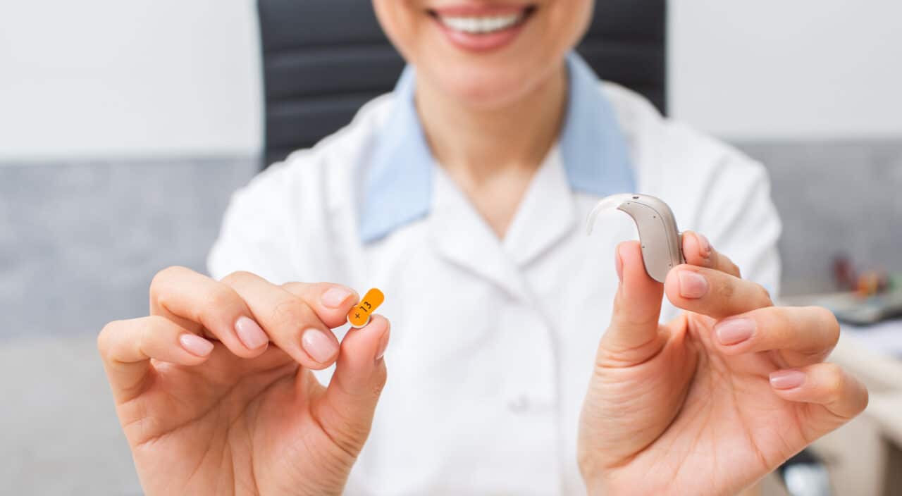 Audiologist holding up a small hearing aid.