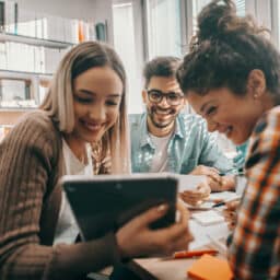 Three college students looking at study materials in the library