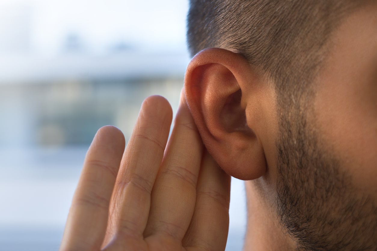 Man holding hand to his ear.