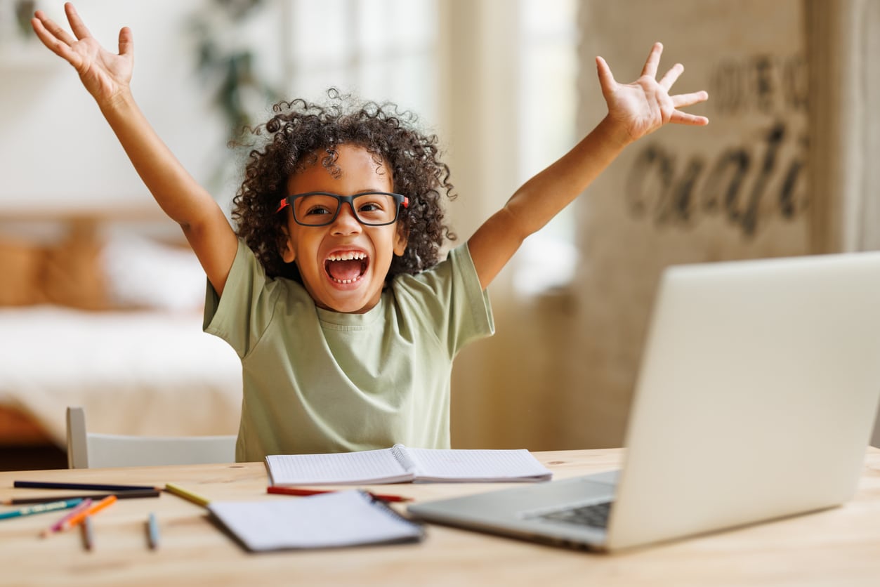 Happy young boy with his arms in the air.