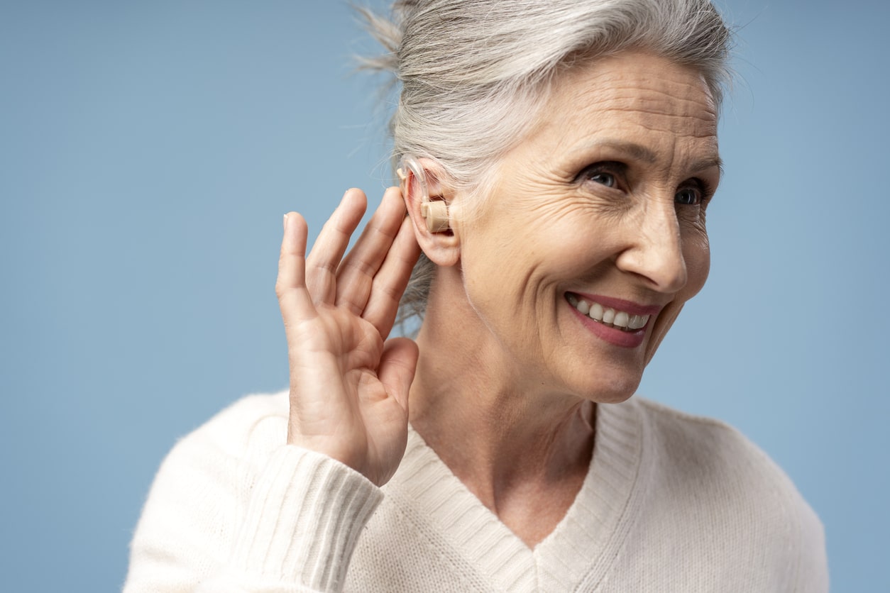 Senior woman showing off her BTE hearing aid.