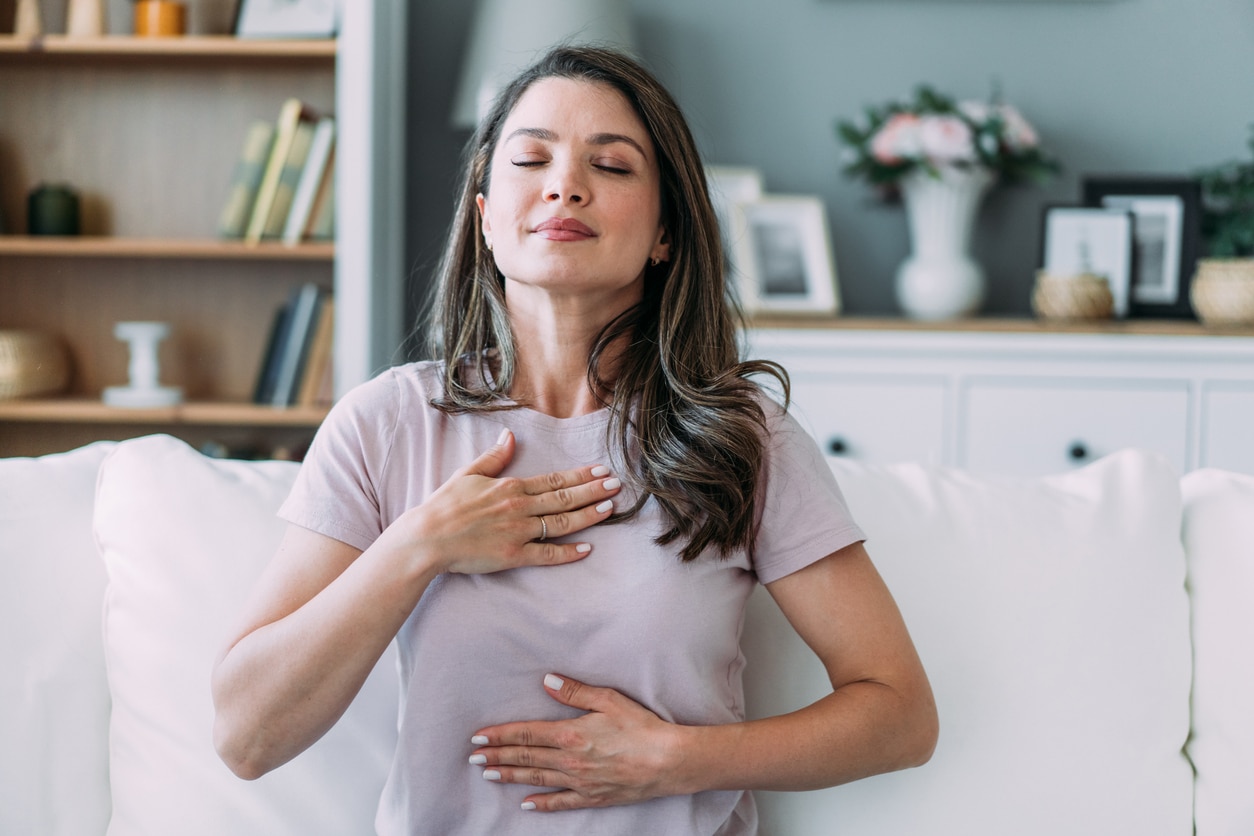 Woman doing calming breathing exercises at home.