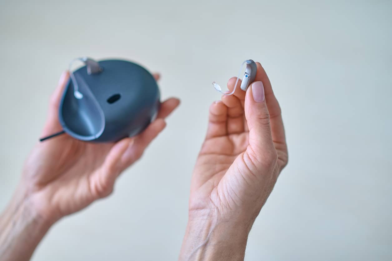 Hand removing a hearing aid from its case.