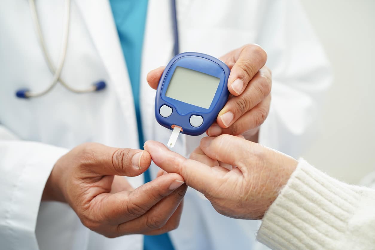 Doctor using digital glucose meter for check sample blood sugar level