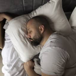 Man Sleeping Cozily on a Bed in His Bedroom in the morning